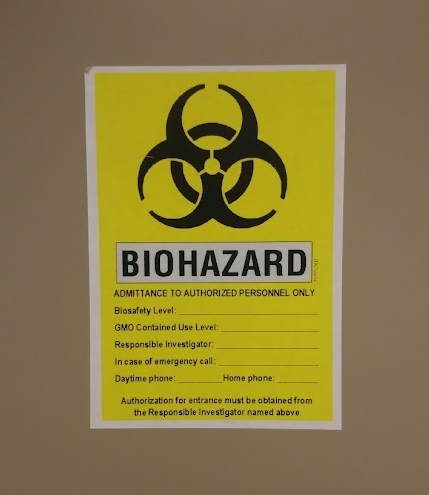 photo of a yellow biohazard sign on the door of a laboratory